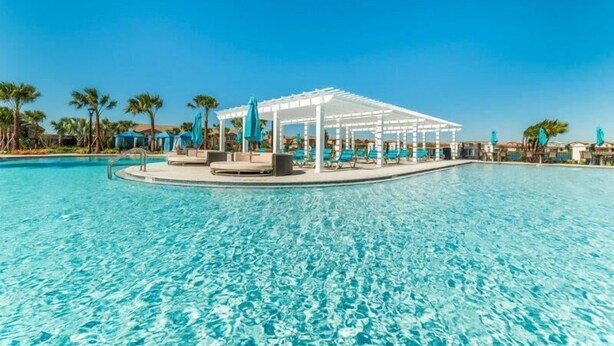 A clear blue pool with a white gazebo and lounge chairs, surrounded by palm trees. - 3700ww (Kissimmee)