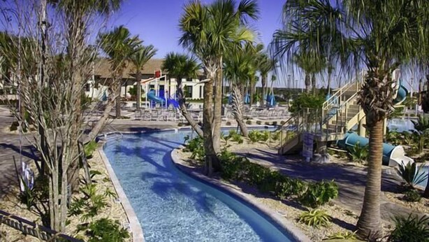 A pool area with a winding water feature, palm trees, and lounge chairs.