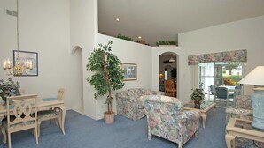 A living room with a dining area, a large potted plant, and a view through a glass door. - Greater Groves 4 Bedroom Home w Pool - 5204GG (Clermont)