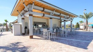 An outdoor patio area with a covered seating area, a bar, and a pool. - Champions Gate 5 Bedroom House w Pool - 4904CG (Davenport)