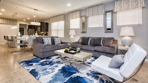 A modern living room with a grey sofa set, a coffee table, and a patterned rug. - Windsor at Westside 5 Bedroom House w Pool - 3715WW (Kissimmee)