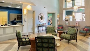 A spacious lobby with a reception desk, seating area, and a large mirror. - Champions Gate 5 Bed Townhouse w Splashpool - 4976CG (Davenport)