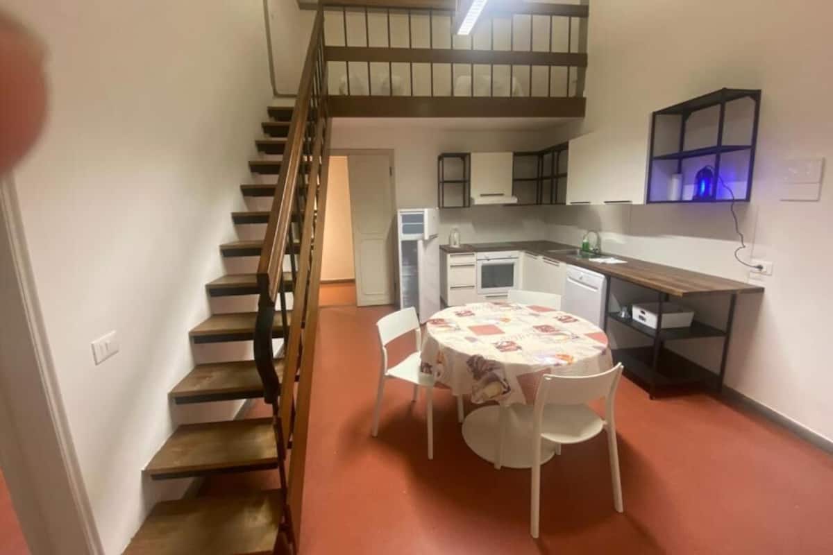 Une cuisine compacte comprenant un coin repas, un escalier et une petite table avec des chaises.