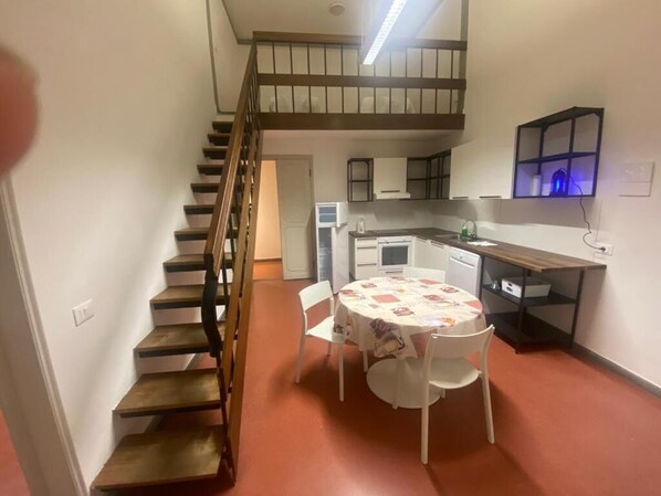 Une cuisine compacte comprenant un coin repas, un escalier et une petite table avec des chaises.