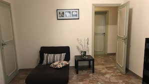 Una habitación con un sofá negro, una mesita con un florero y un suelo estampado con diseño de piedra.