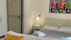 Un dormitorio con cama, mesita de noche, lámpara y un cuadro de scooters en la pared.