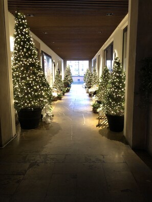 Un couloir décoré de sapins de Noël et d’illuminations, qui mène à une sortie lumineuse.