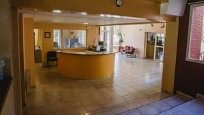 A reception area with a curved counter, a chair, and a desk. - Convivir Departamentos (Córdoba)