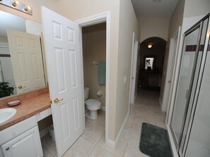 A hallway leading to a bathroom with a toilet, a sink, and a mirror. - Cumbrian Lakes 634 (Kissimmee)