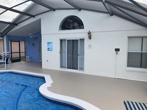 A pool area with a covered deck, a sliding glass door, and a small outdoor seating area.