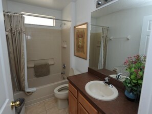 A bathroom with a bathtub, toilet, sink, and a shower curtain. - Terra Verde 705 (Kissimmee)
