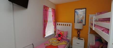 A child's bedroom with a single bed, a nightstand, a TV mounted on the wall, and a bunk bed with children's bedding.