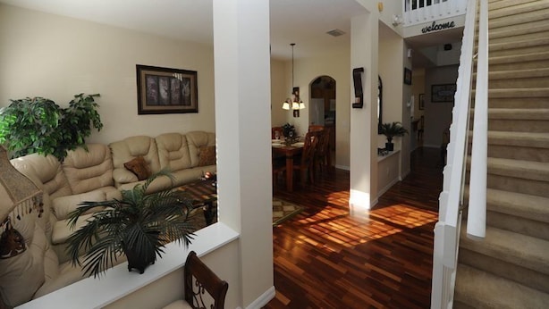 A spacious living room with a beige sofa, a dining area, and a staircase. - Cumbrian Lakes 25 (Kissimmee)