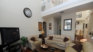 A living room with a television, two sofas, a coffee table, and a clock on the wall. - Cumbrian Lakes 25 (Kissimmee)