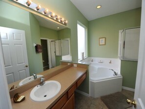 A bathroom with a sink, vanity, mirror, bathtub, and a shower enclosure.