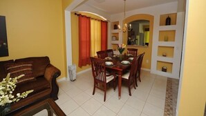 A dining area with a wooden table and chairs, yellow walls, and a red curtain. - Terra Verde 665 (Kissimmee)