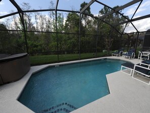 An indoor swimming pool with a hot tub, surrounded by a glass enclosure, and equipped with lounge chairs.