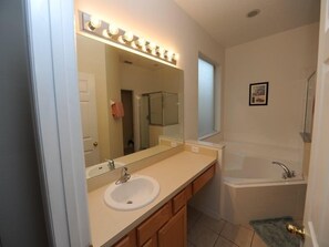 A bathroom with a sink, mirror, vanity, and bathtub.