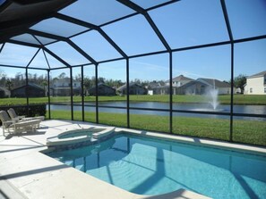 Área da piscina com vista para um lago e casas ao fundo.