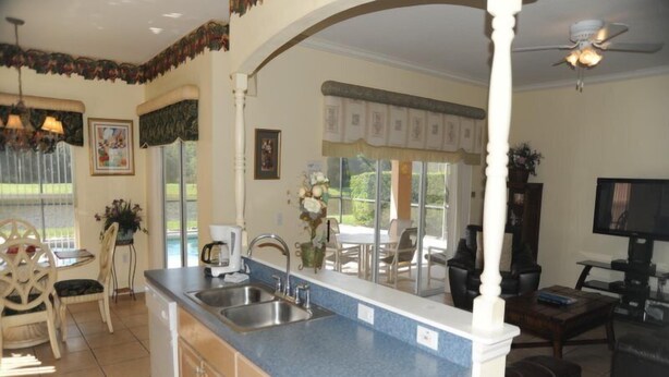 A kitchen with a blue countertop, a sink, and a dining area with a table and chairs. - Cumbrian-lakes-38 (Kissimmee)