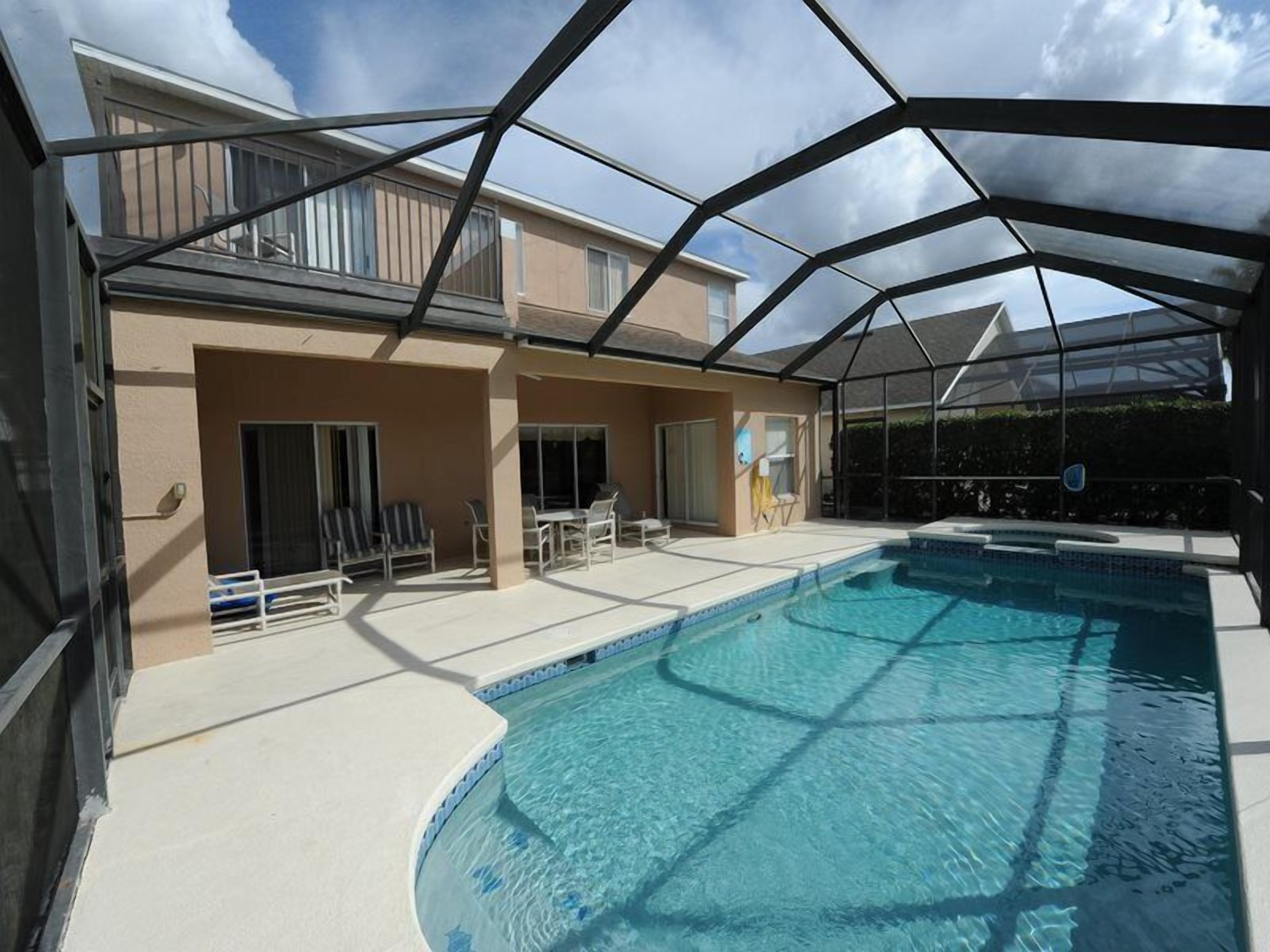 A covered outdoor swimming pool with a house in the background.