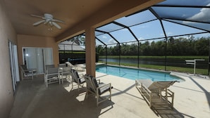 A covered outdoor area with a pool, lounge chairs, and a ceiling fan. - Cumbrian-lakes-38 (Kissimmee)