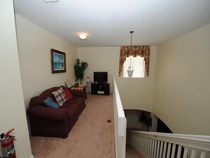 A living room with a sofa, television, and a staircase. - Cumbrian-lakes-38 (Kissimmee)