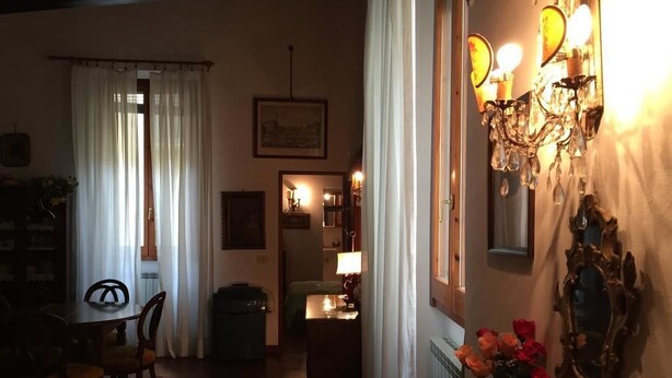 Une pièce faiblement éclairée, avec une table à manger, des chaises, un radiateur et un miroir au mur.