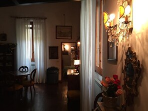 Una habitación tenuemente iluminada con una mesa de comedor, sillas, un radiador y un espejo en la pared.