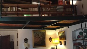 Un salon chaleureux avec un canapé vert, une bibliothèque en bois et un tableau accroché au mur.
