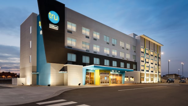 A modern hotel with a prominent 'tru' logo, multiple floors, and a well-lit entrance.