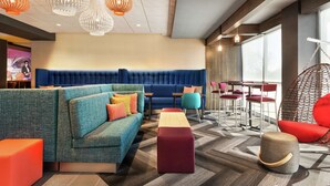 A modern lounge area with a blue sofa, colorful ottomans, and a variety of seating options including a red chair and a wicker chair.