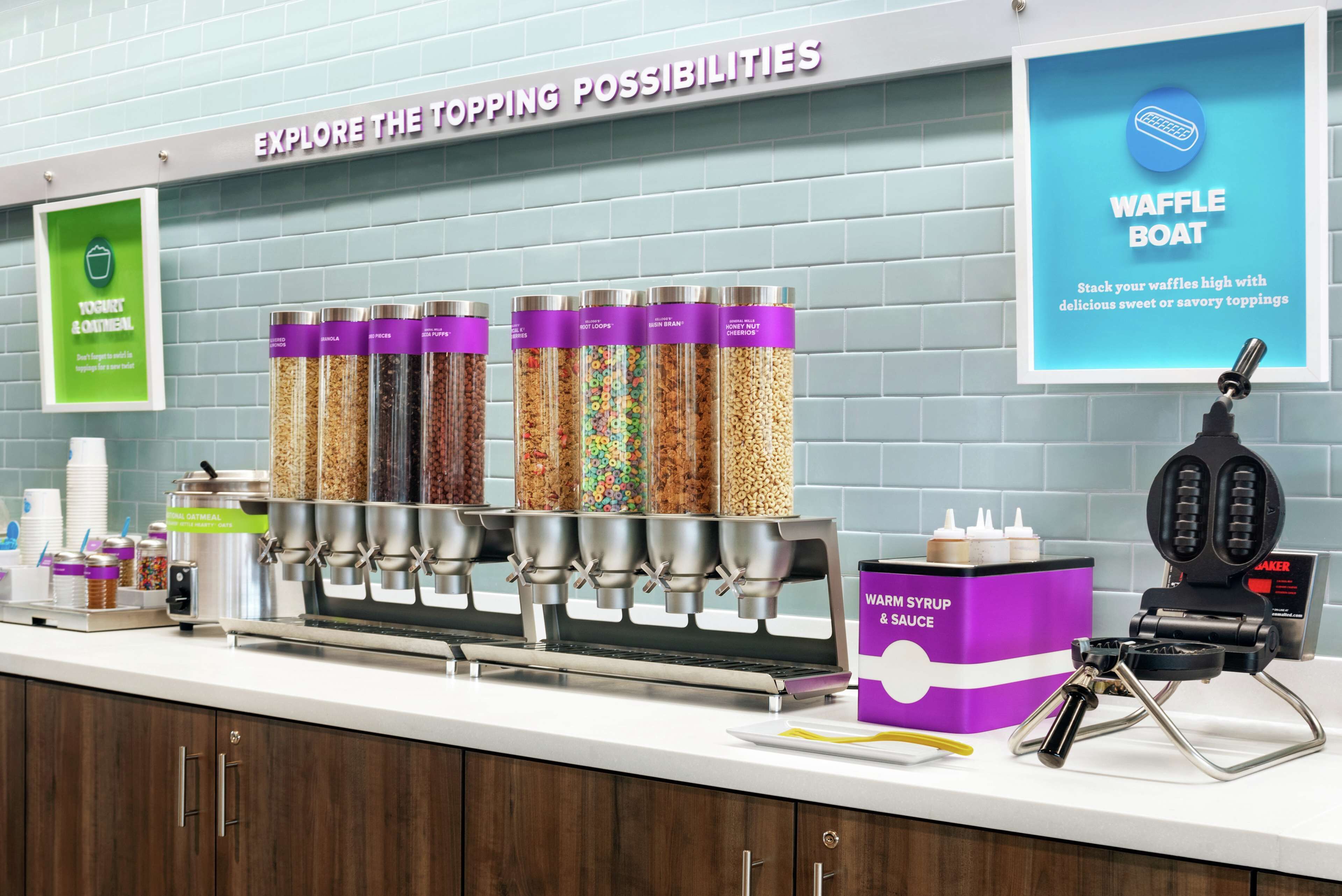 A breakfast bar with various food dispensers, a waffle boat, and a syrup and sauce dispenser.