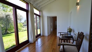 Une pièce spacieuse dotée de grandes fenêtres, d’un plancher en bois et d’un coin repas avec des chaises et une table.