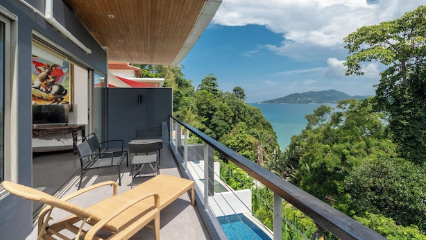 A balcony with wicker furniture, a pool, and a view of a lake and mountains. - Villa 8 oceanfront pool villa (Tambon Patong)