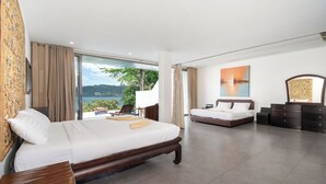 A modern hotel room with a large bed, a smaller bed, a desk, and a view of the outdoors. - Villa 8 oceanfront pool villa (Tambon Patong)
