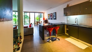 A modern kitchen with a large island, red bar stools, and a view of the outdoors. - Villa 8 oceanfront pool villa (Tambon Patong)