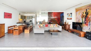 A spacious living area with a dining table, sofa, and a staircase leading to an upper floor. - Villa 8 oceanfront pool villa (Tambon Patong)