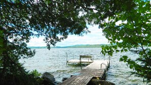 A wooden dock extending into a calm lake, surrounded by rocks and trees.