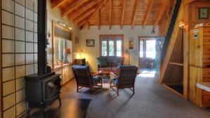 A cozy living room with a fireplace, wooden ceiling, and a comfortable seating area.