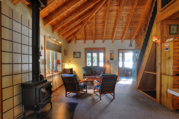A cozy living room with a fireplace, wooden ceiling, and a comfortable seating area.