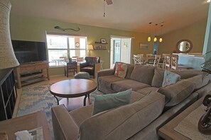 Una sala de estar con un sofá modular, un televisor y un comedor con mesa y sillas.