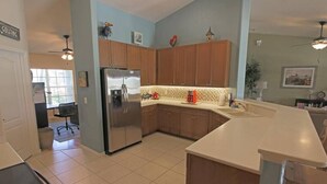Une cuisine moderne avec des meubles en bois, un réfrigérateur en acier inoxydable et un plan de travail blanc.