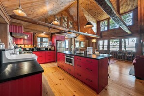 Una cocina amplia con pisos de madera, armarios rojos y una isla grande.