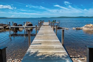 A wooden pier extending into calm water with clear skies and distant hills.