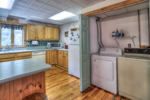A compact kitchen with wooden cabinets, a microwave, a refrigerator, and a washing machine.