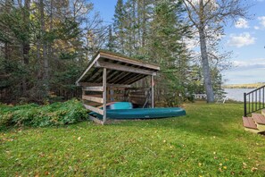 A wooden cabin with a covered porch and a canoe.