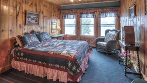 Een gezellige slaapkamer met een groot bed, een stoel, een tafel en een raam met uitzicht op de omgeving.