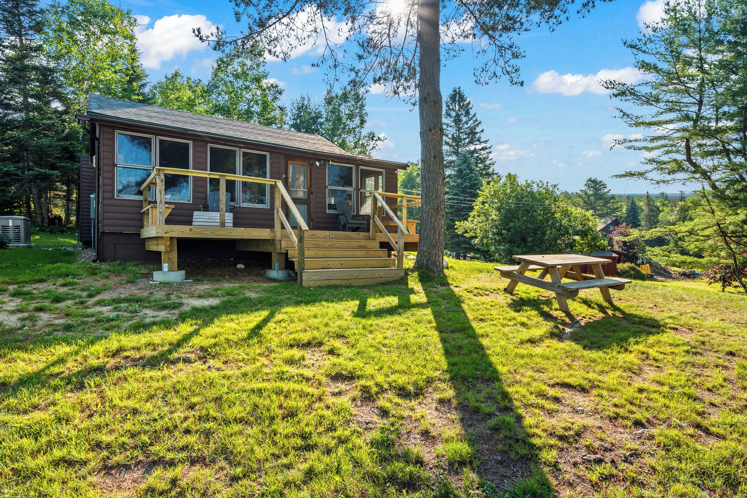 Une cabane dotée d’une terrasse, d’une table de pique-nique et offrant une vue sur la forêt environnante.