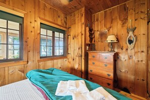 A wooden room with a bed, dresser, and window.
